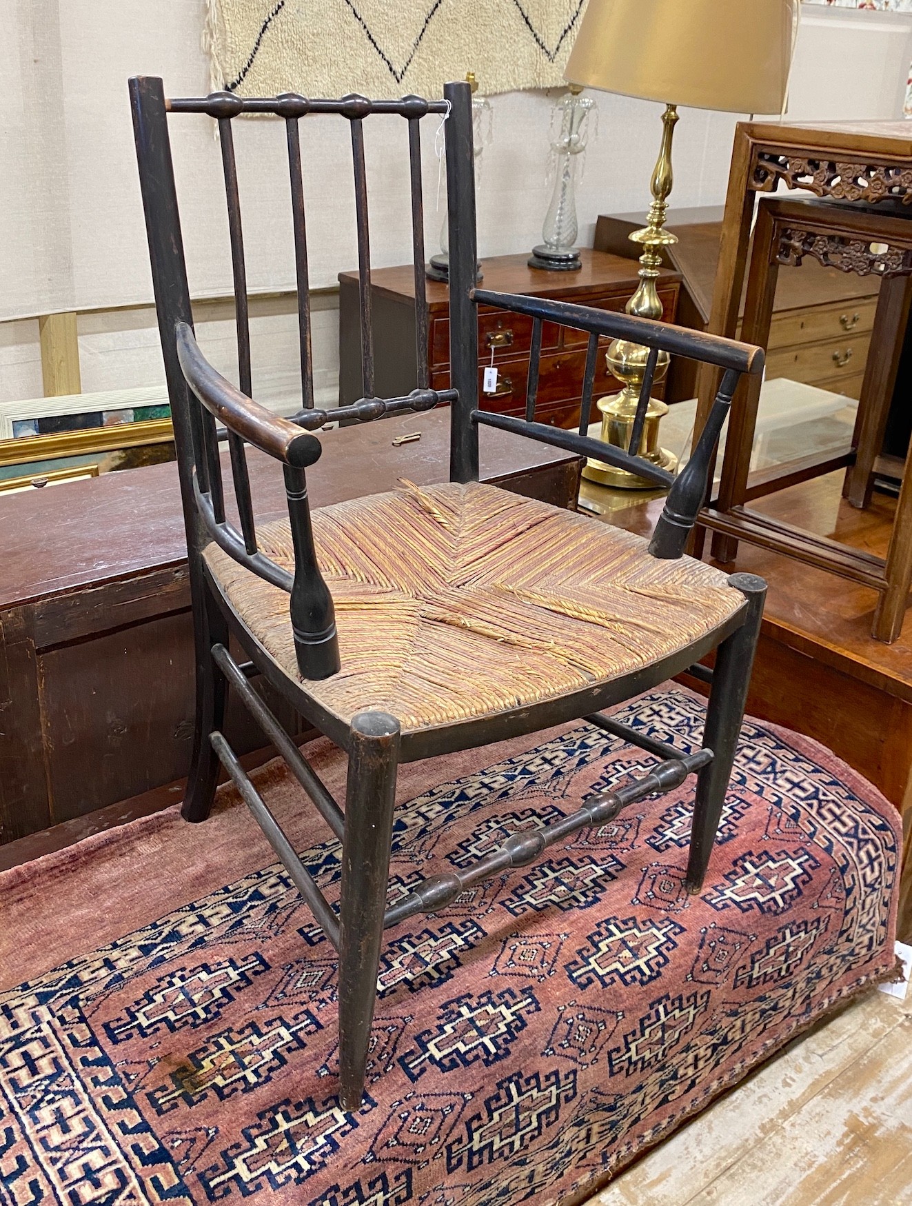 A Victorian ebonised Morris style Sussex chair with rush seat, width 58cm, depth 47cm, height 87cm